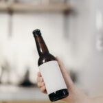 A brown glass beer bottle, unopened, with a blank white label